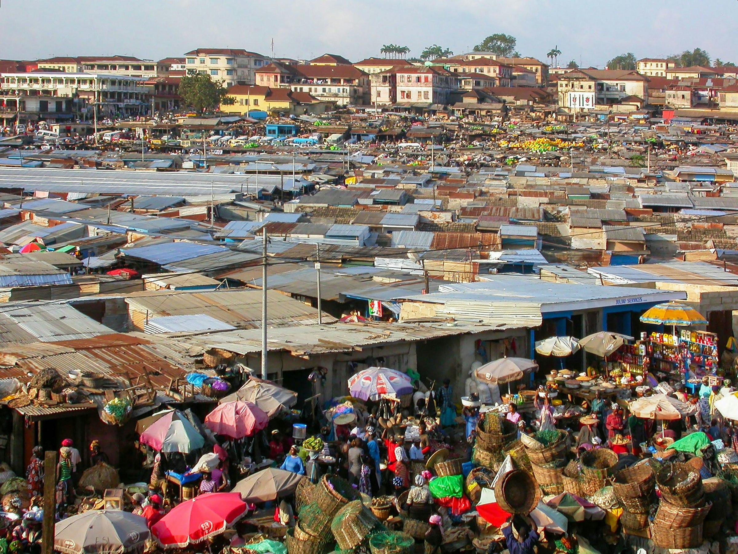 A dense market quarter seen from above, corrugated roofs and stalls running to the edge of a town.